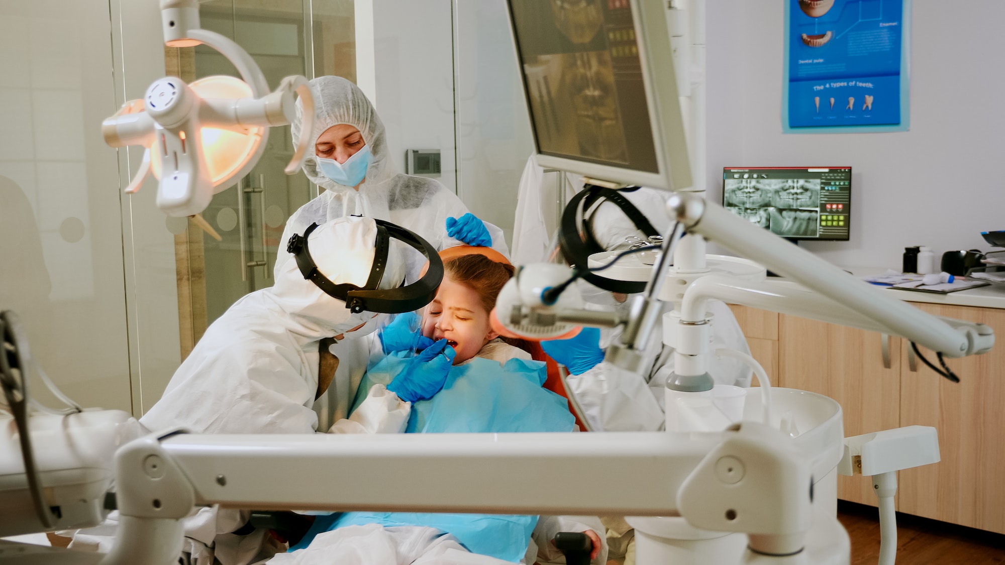 Child on dental chair in dentist surgery treated with dental drill