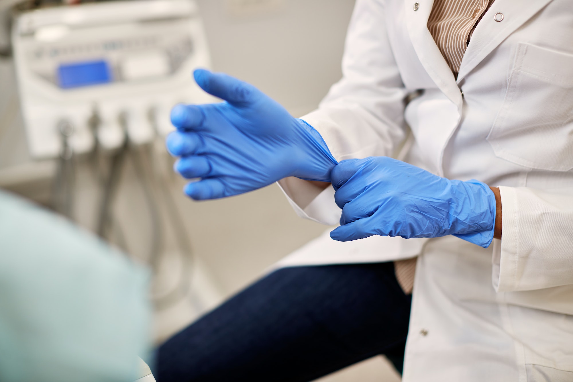 Close-up of dentist using surgical gloves while working at dental clinic.