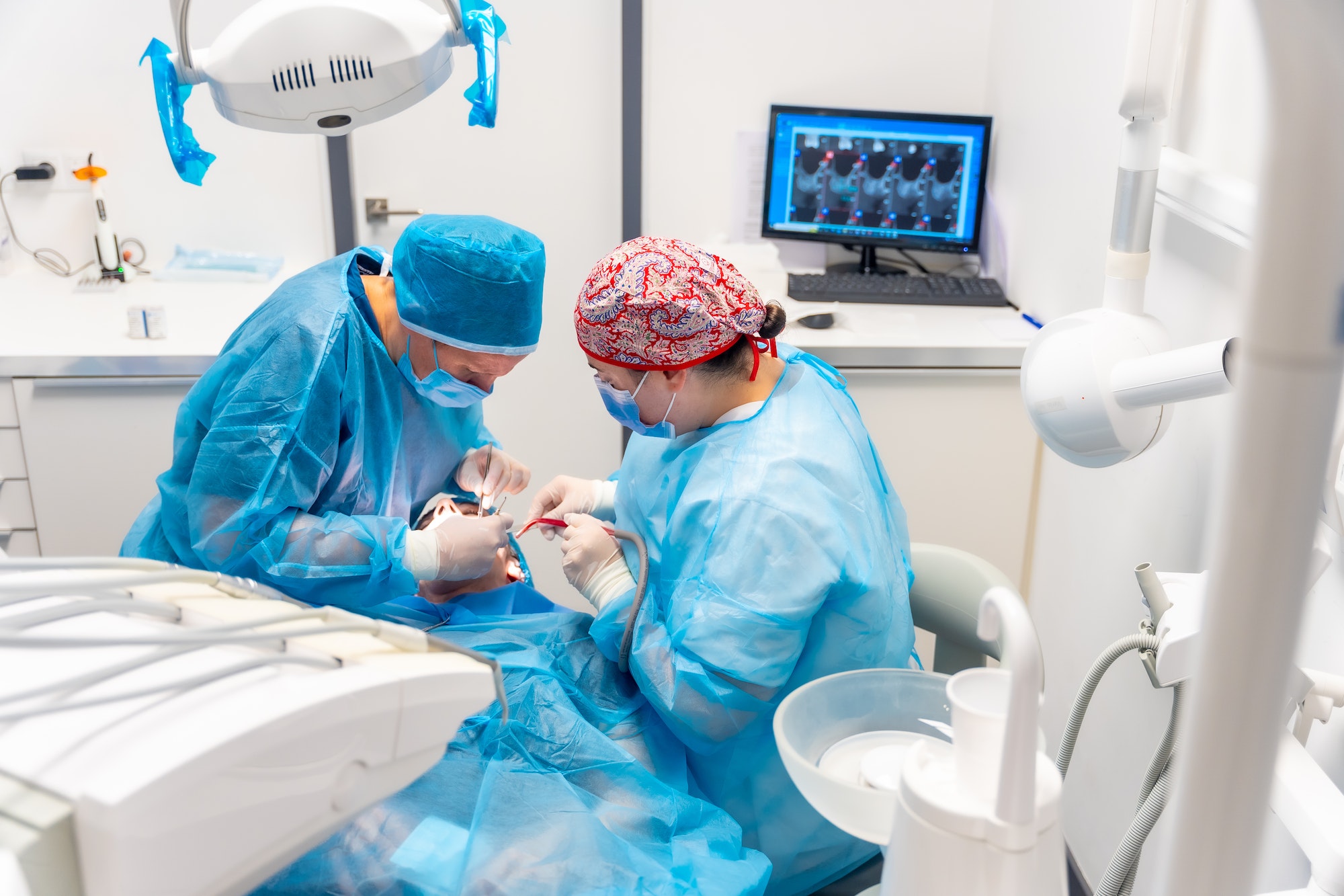 Dental clinic, detail of dentists with blue suits performing an implant, view from above operation