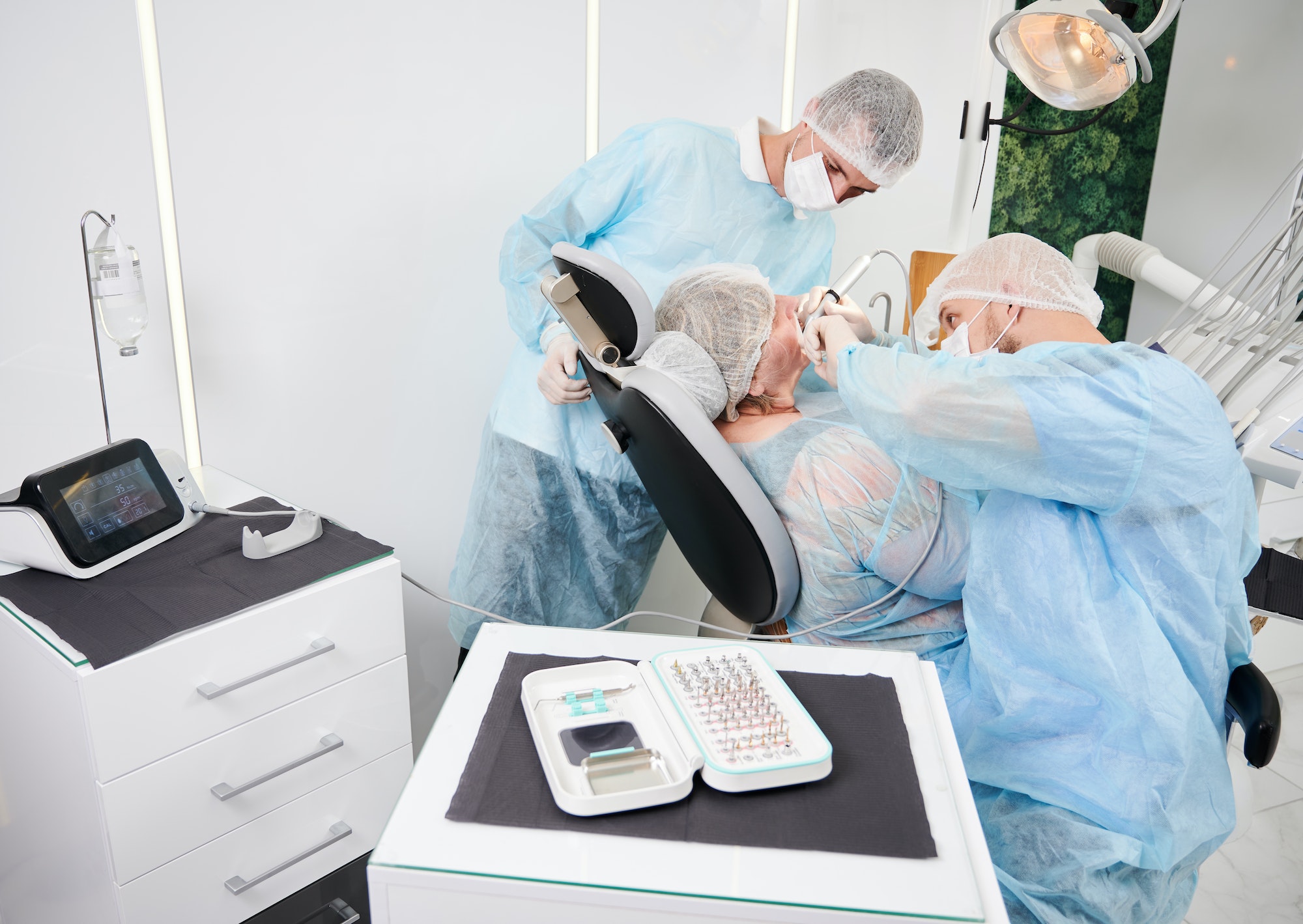 Dentist using dental implant machine during implantology procedure.