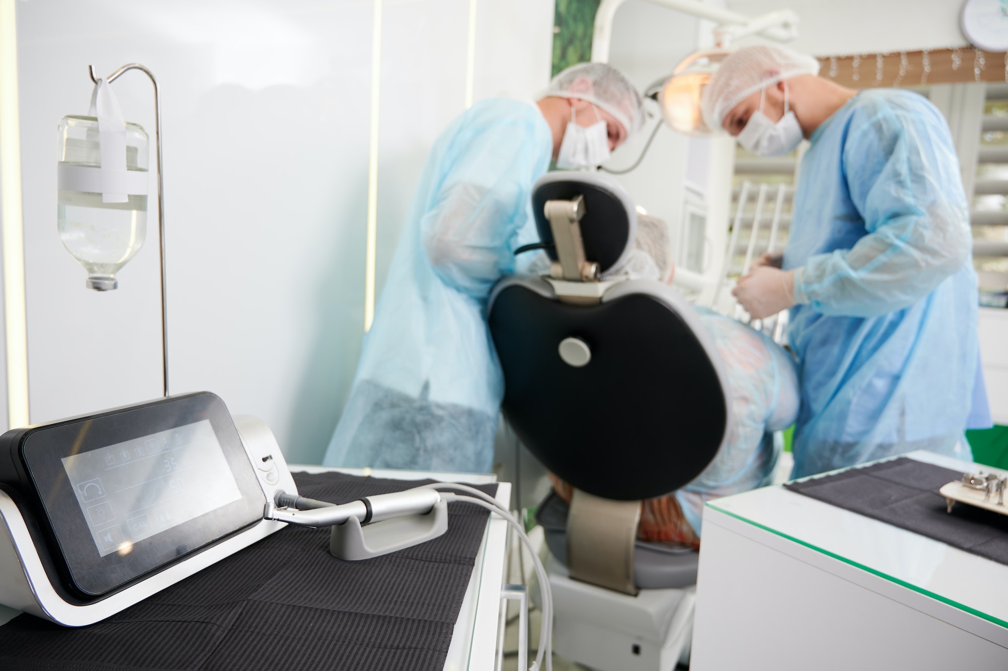 Dentists using dental implant machine in modern dental office.