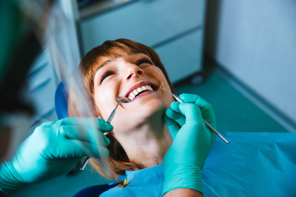 Smiling woman mouth under treatment at dental clinic - Oral healthcare concept