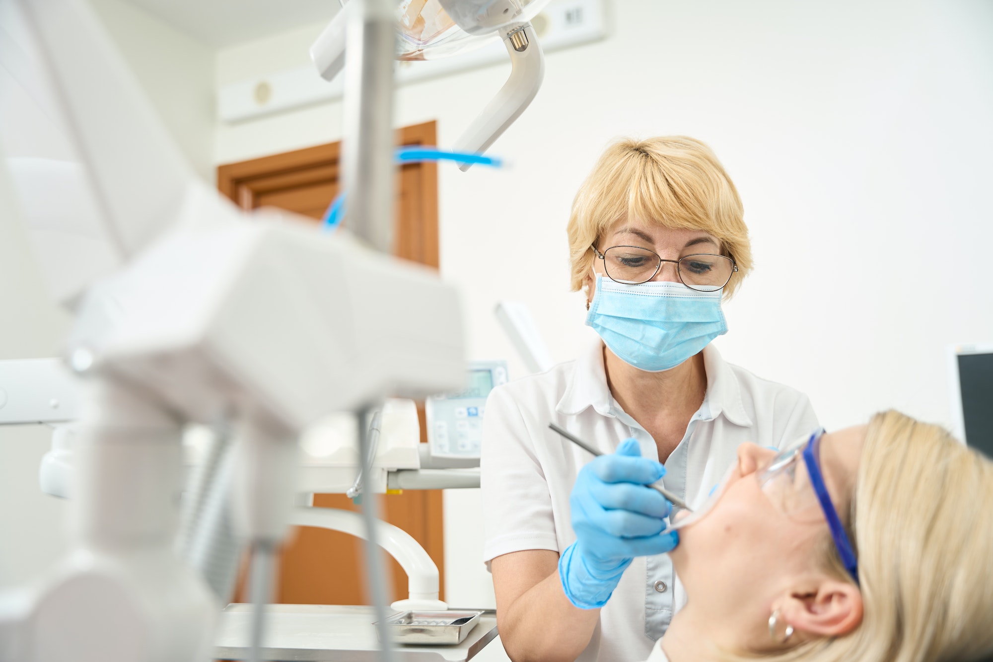 Woman dentist wearing a protective mask treats her teeth