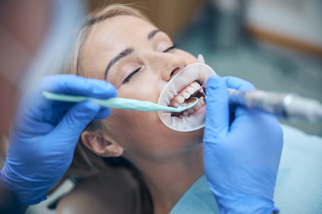 Young woman having teeth treated at dentist